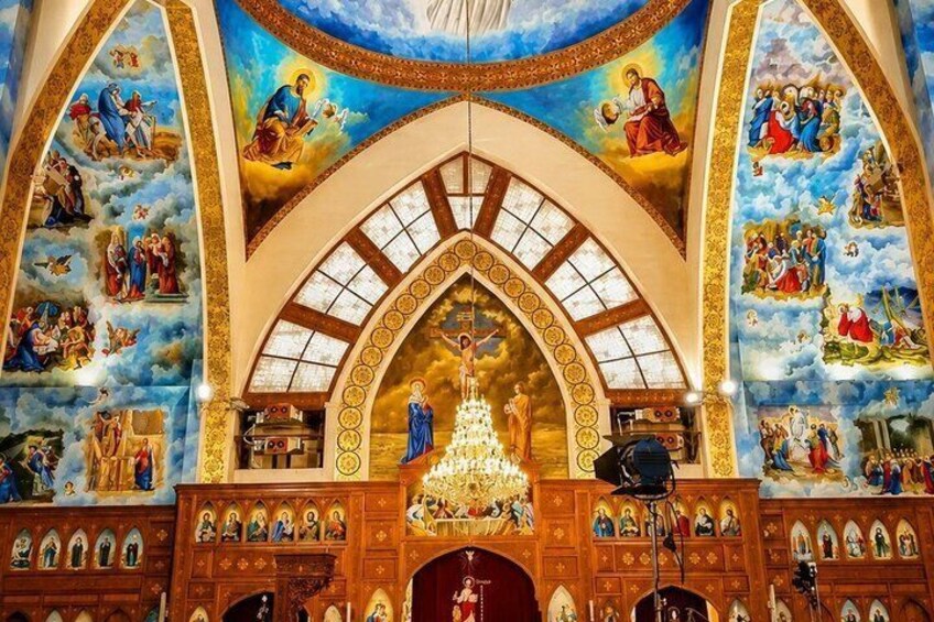 A church interior with a central altar, stained glass windows, and religious murals. 4