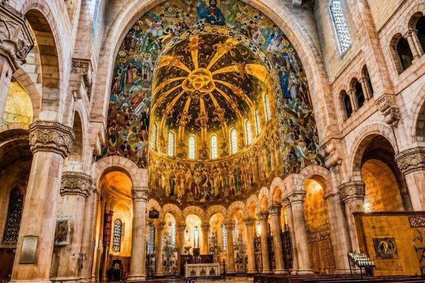 An ornate cathedral interior with a large dome, arched windows, and detailed wall frescoes. 5