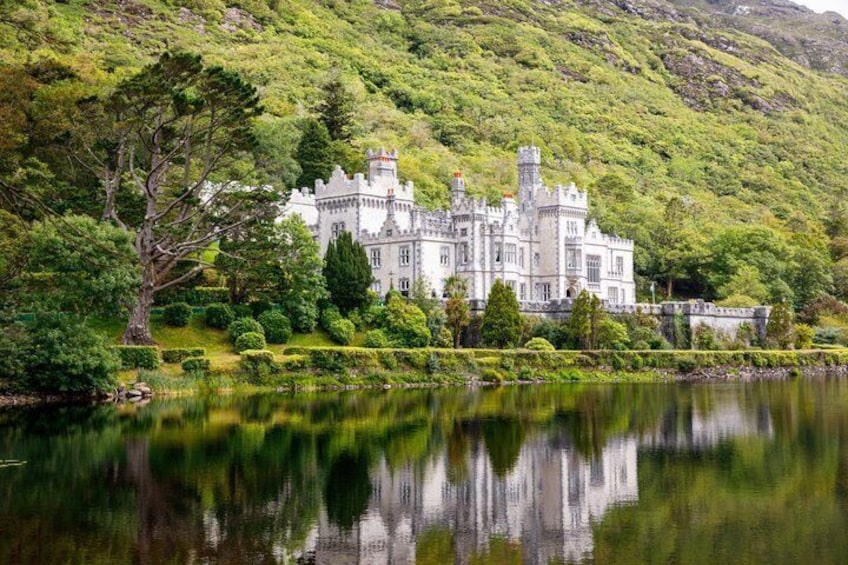 A castle with a lake in front, surrounded by lush greenery and hills. 1