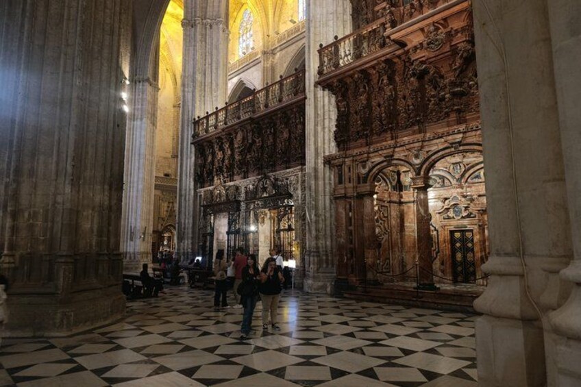 A cathedral interior with high vaulted ceilings, large columns, and ornate wood carvings. 5
