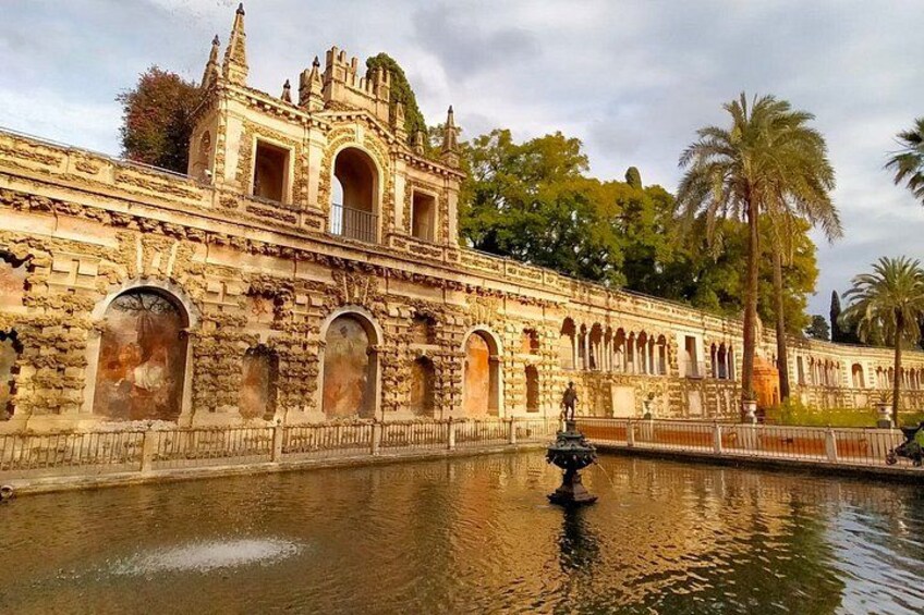 A historic building with arched windows and a fountain in the foreground. 2