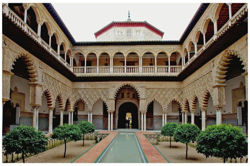 A courtyard with arches, a central pool, and a building with a red-tiled roof. 1