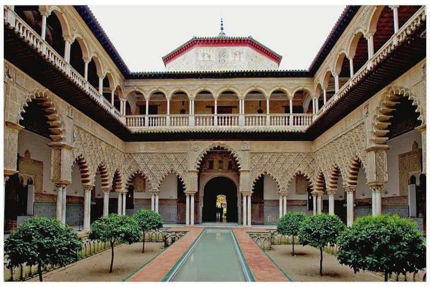 A courtyard with arches, a central pool, and a building in the background. 1
