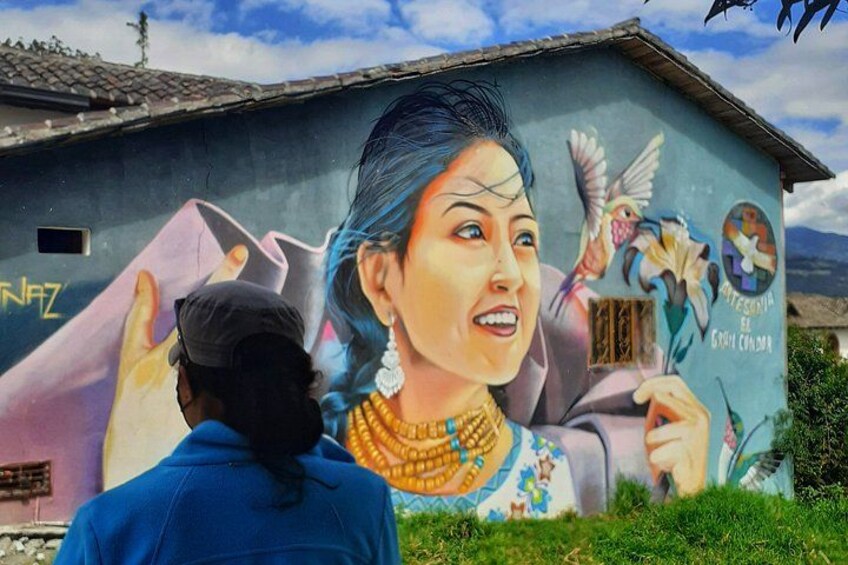 A mural on a building with a person in traditional attire, a bird, and a flower. 5
