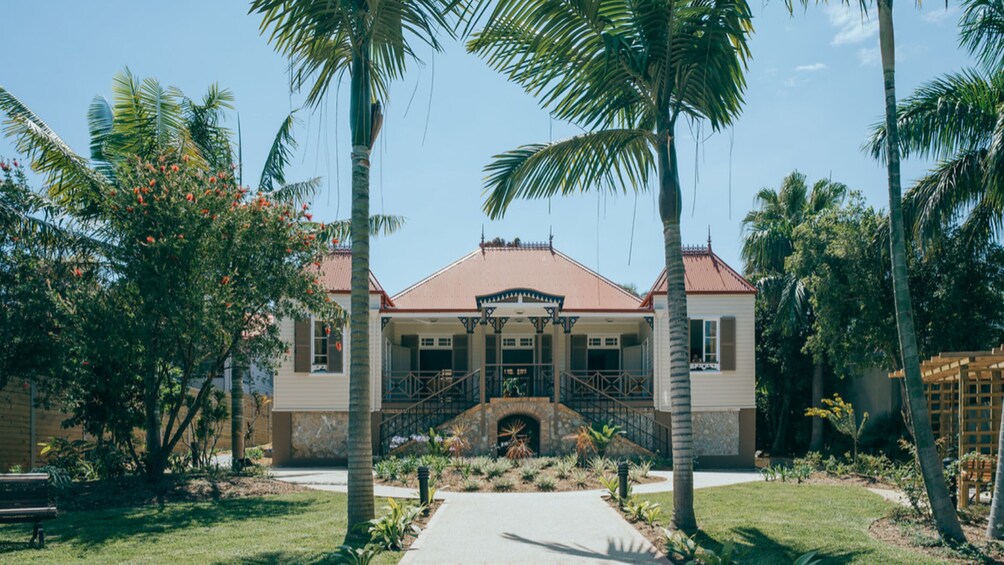 A house with a red roof, surrounded by palm trees and a garden. 2