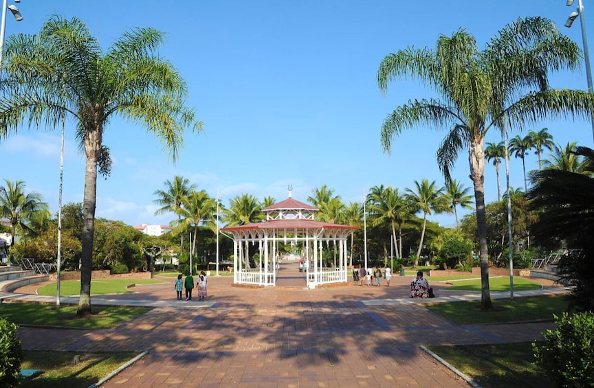 A gazebo in a park with palm trees and a clear sky. 4
