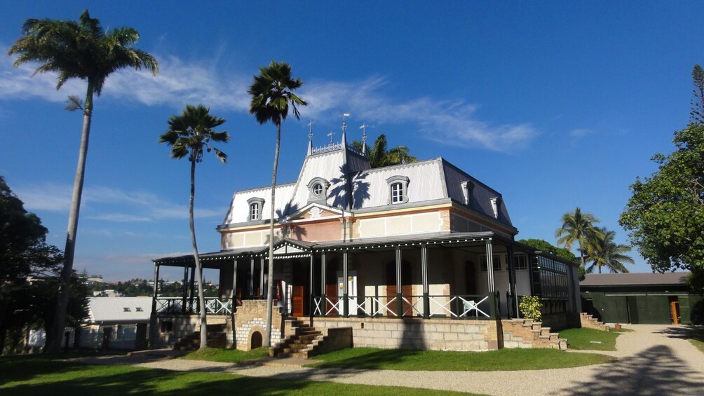 A historic building with a white facade, a dome, and a covered porch. 1