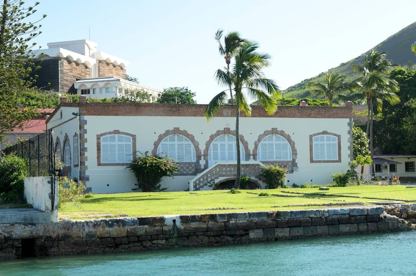 A coastal building with arched windows and a palm tree in front. 5