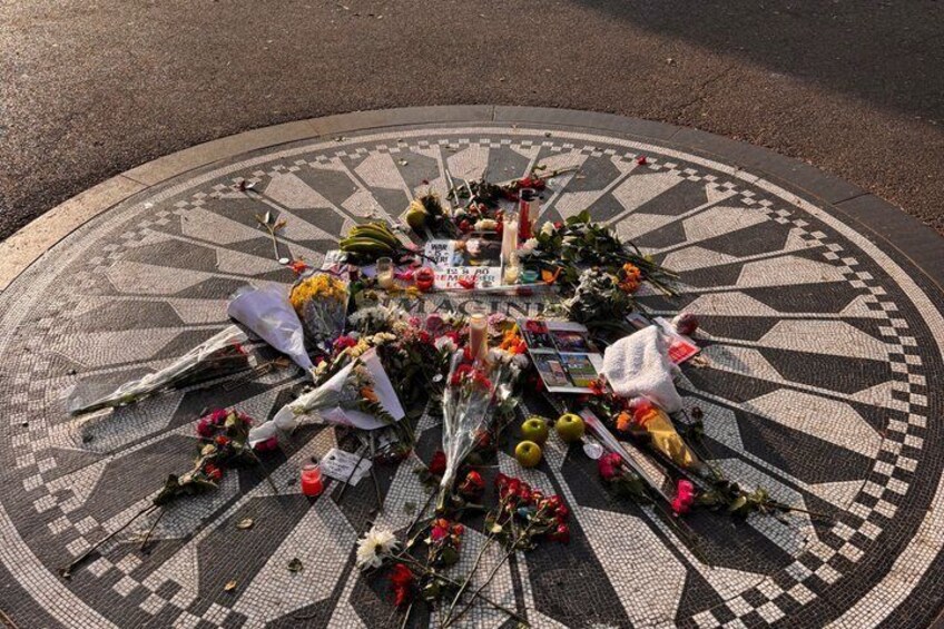 A memorial with flowers and candles arranged on a patterned pavement. 2
