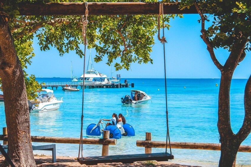 Une balançoire en bois surplombant une marina, avec des bateaux et une mer d’un bleu limpide. 5