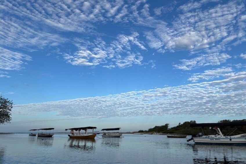 Calm water with boats, a clear sky, and a distant shoreline. 2