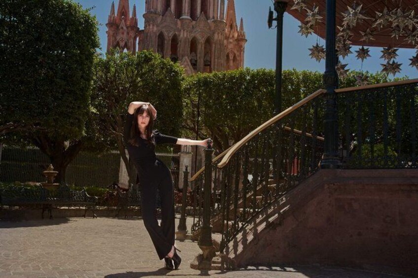 A person in black attire posing on a stone staircase with a gothic building in the background. 2