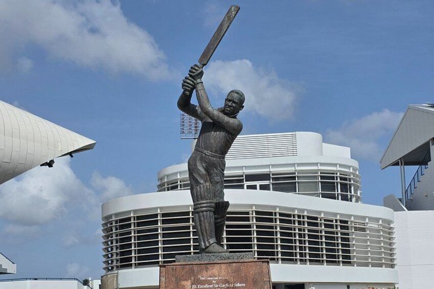 A cricket statue in front of a modern building with a circular design. 5