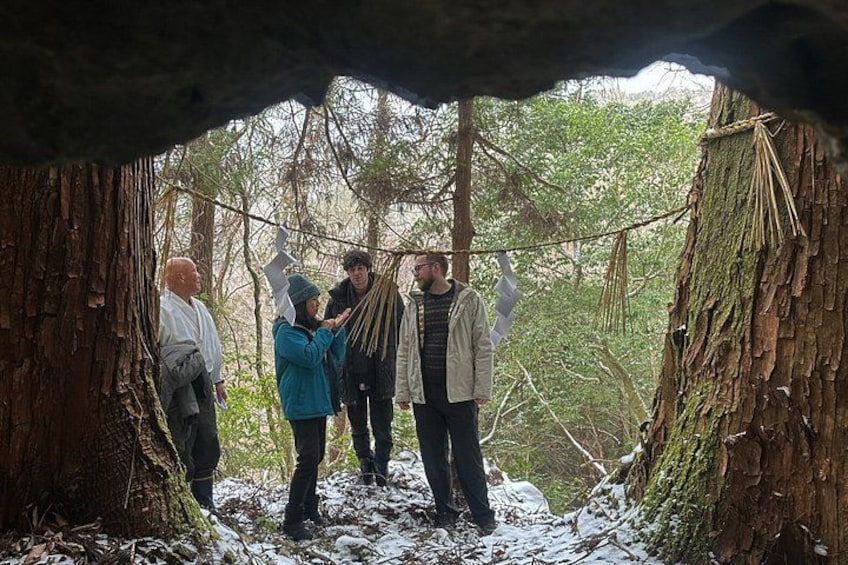 A group of people standing in a forested area with trees and snow on the ground. 1