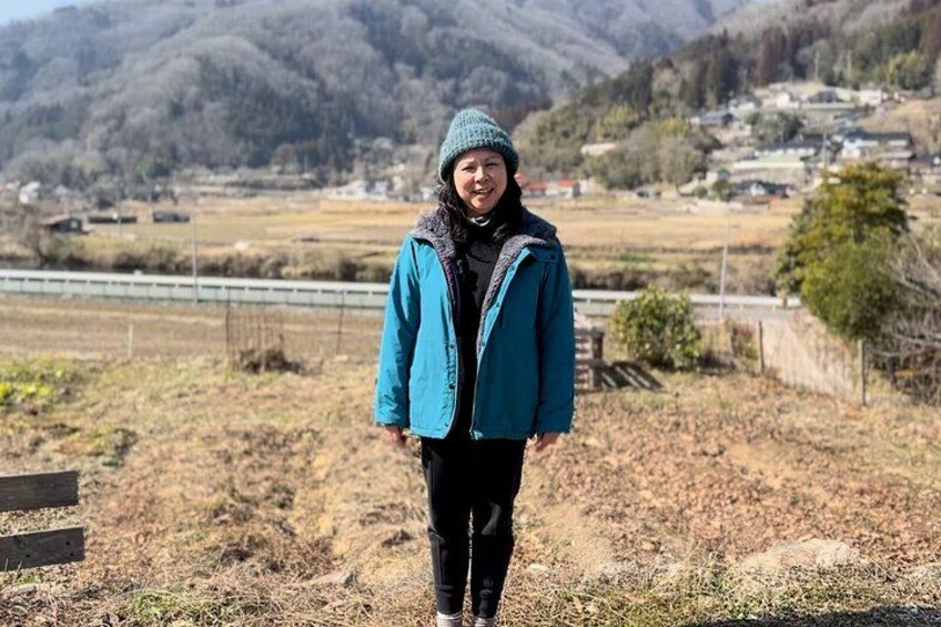 A person standing in a rural area with mountains in the background. 4