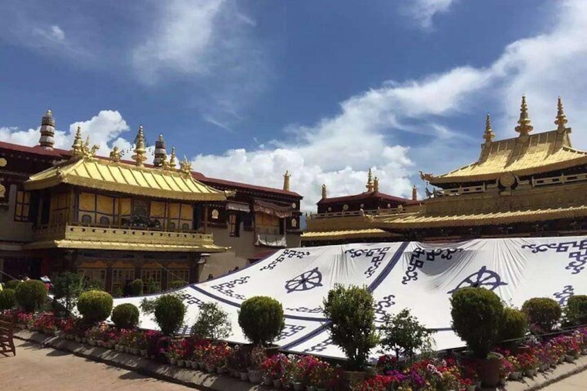 A traditional building with golden roofs and a large white tent with blue patterns. 1