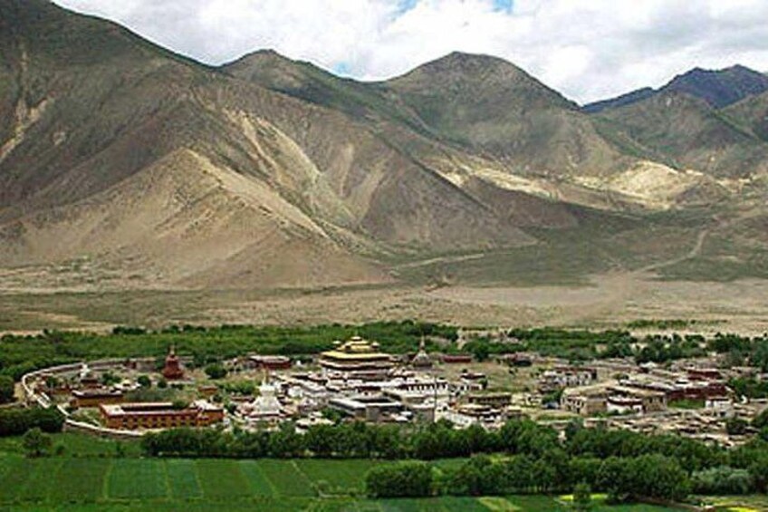 A mountainous landscape with a monastery complex surrounded by green fields. 5