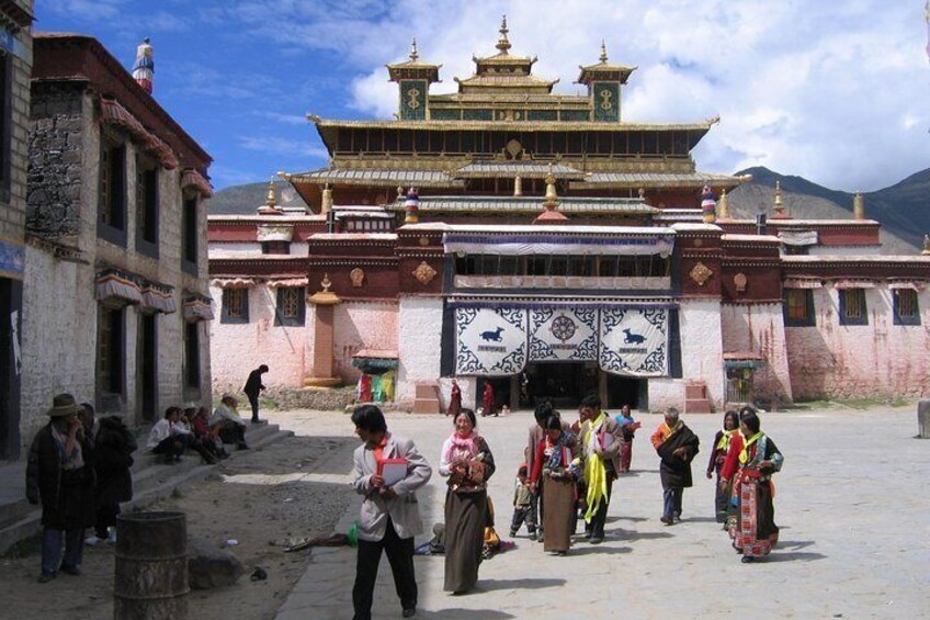 A traditional building with a tiered roof and ornate decorations, surrounded by people in traditional attire. 1