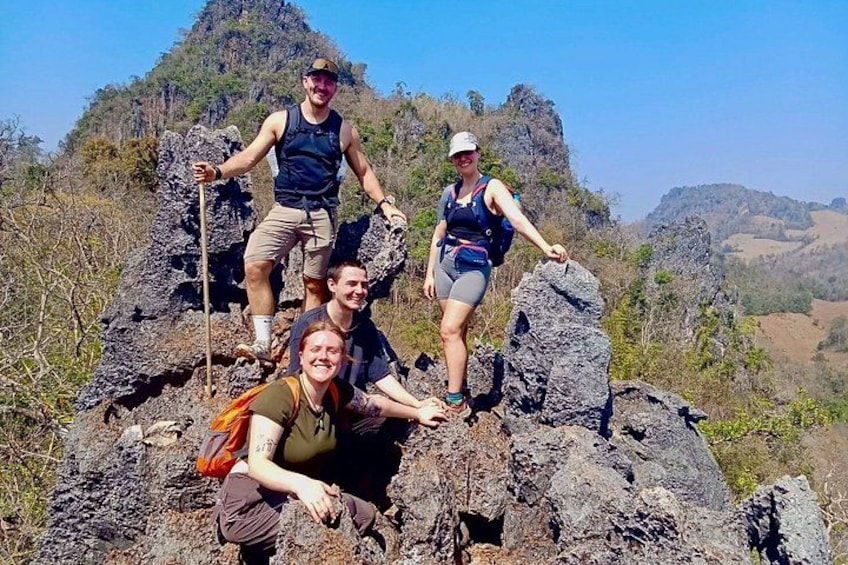 A group of hikers on rocky terrain with a mountainous backdrop. 1
