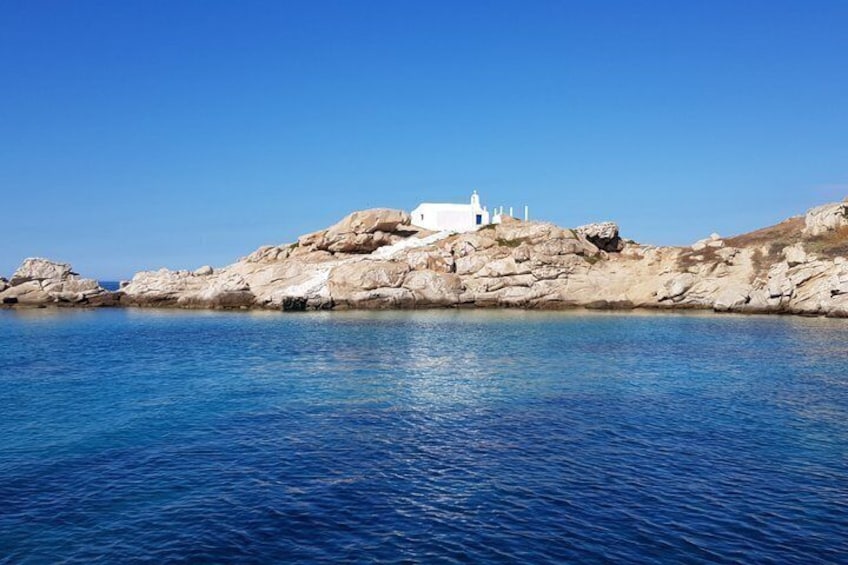 A white building on a rocky outcrop by a calm sea. 3
