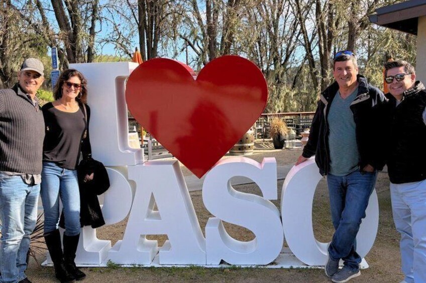 A group of people standing in front of a large sign with 'I ♥ PASO' and a red heart. 1