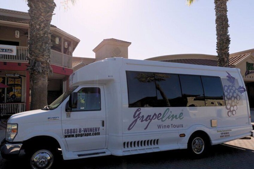 A white van with 'Grapeline Wine Tours' and a website address parked in front of a building with palm trees. 3