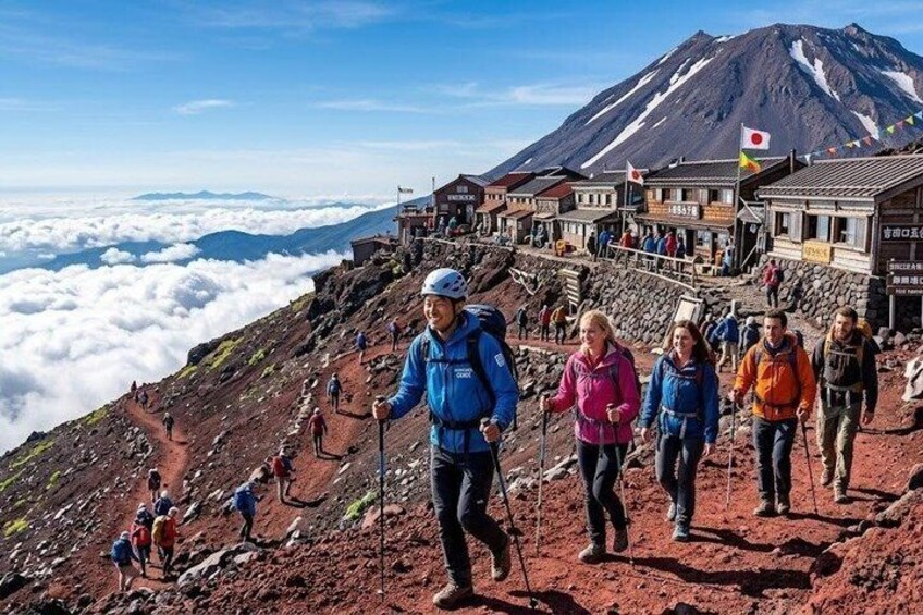 A group of hikers on a mountain trail with a view of a snow-capped peak and traditional buildings in the background. 1
