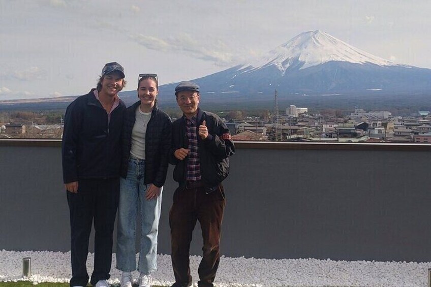 Three people standing on a rooftop with a view of a snow-capped mountain in the background. 5