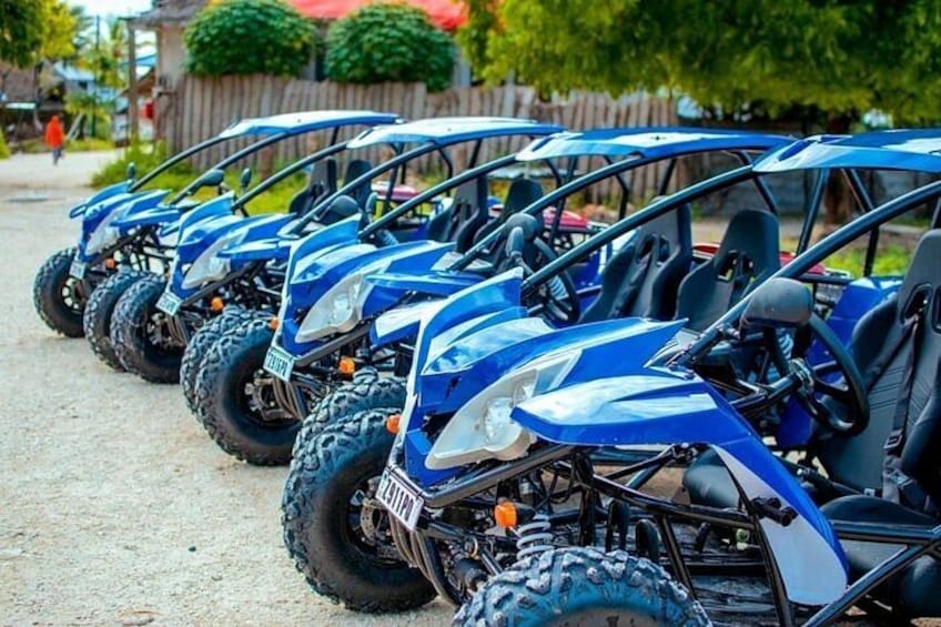 A row of blue off-road vehicles parked on a gravel surface. 1