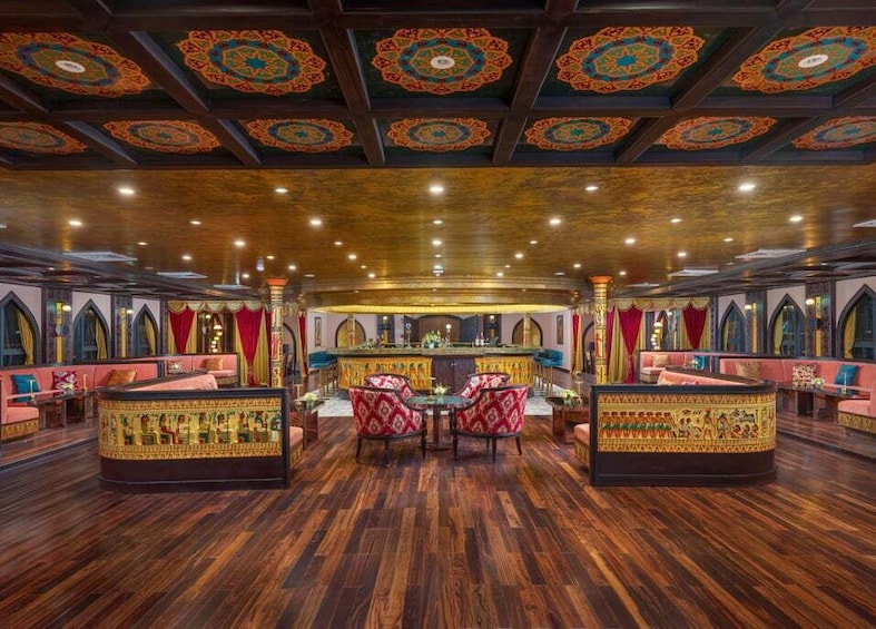 A bar with ornate decor, wooden flooring, and cushioned seating. 2