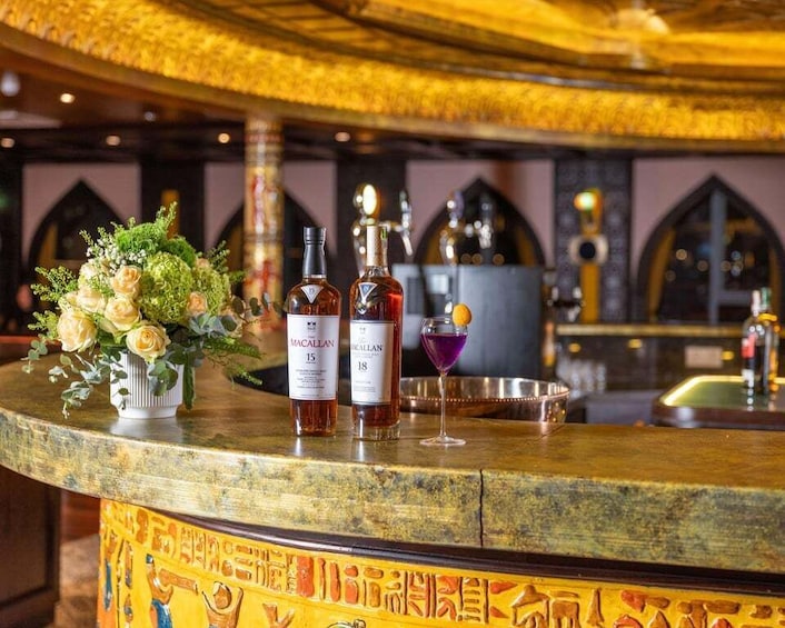A bar counter with Macallan whiskey bottles, a floral arrangement, and a cocktail glass. 4