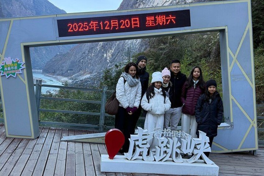 A group of people posing in front of a sign with a date and a location name. 4