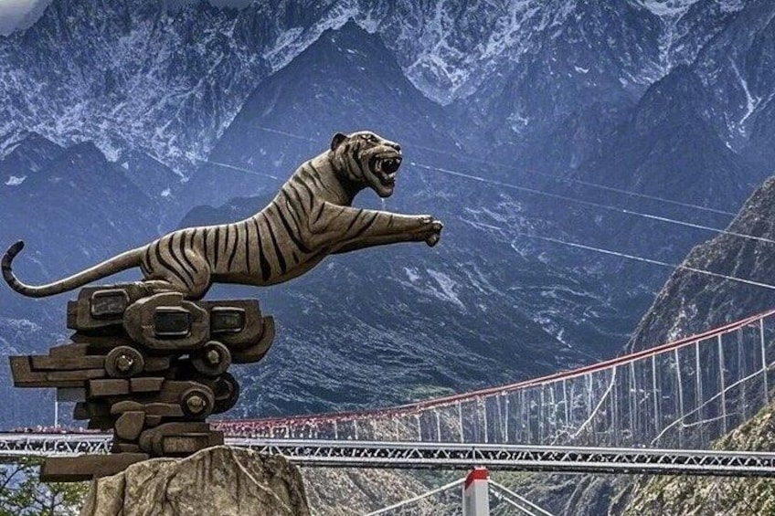 A tiger statue on a bridge with a mountainous backdrop. 1