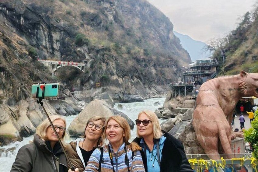 A group of people taking a selfie with a river and a large statue in the background. 3