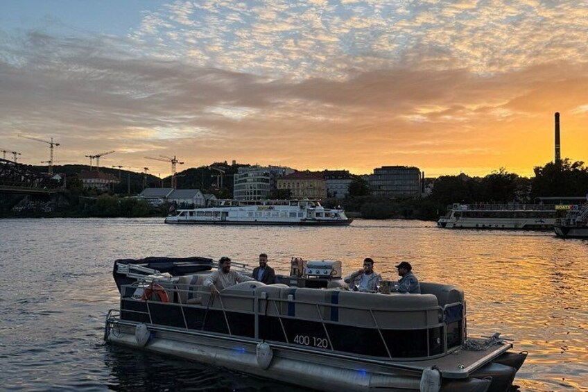 A boat with people on it, a river, and buildings in the background. 1