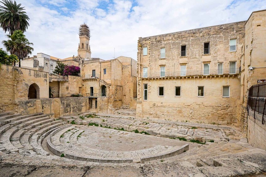 An ancient amphitheater with stone steps and a tower in the background. 5