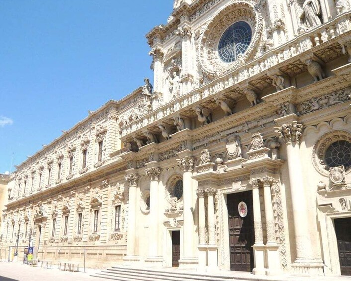 A grand, ornate building with intricate sculptures and columns, featuring a large circular window and multiple doorways. 2