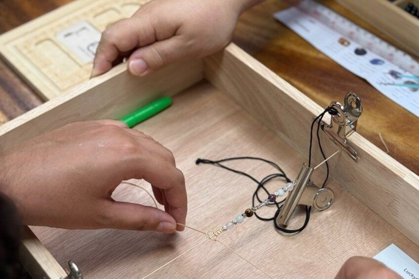 Hands assembling a mechanical device with wires and a green pen on a wooden surface. 2