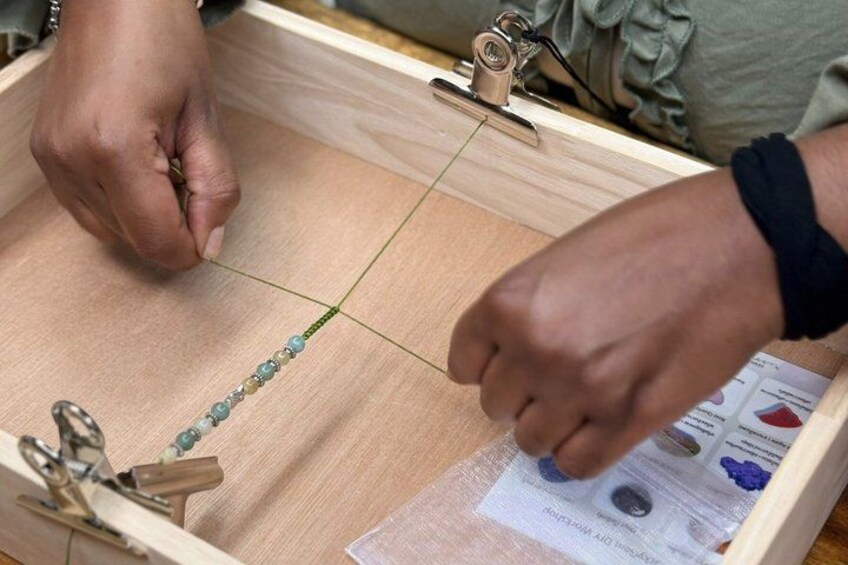 Hands threading beads onto a string. 3