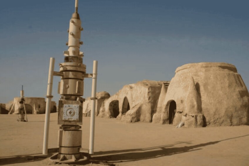 A desert landscape with a large, cylindrical structure and traditional mud-brick buildings. 5