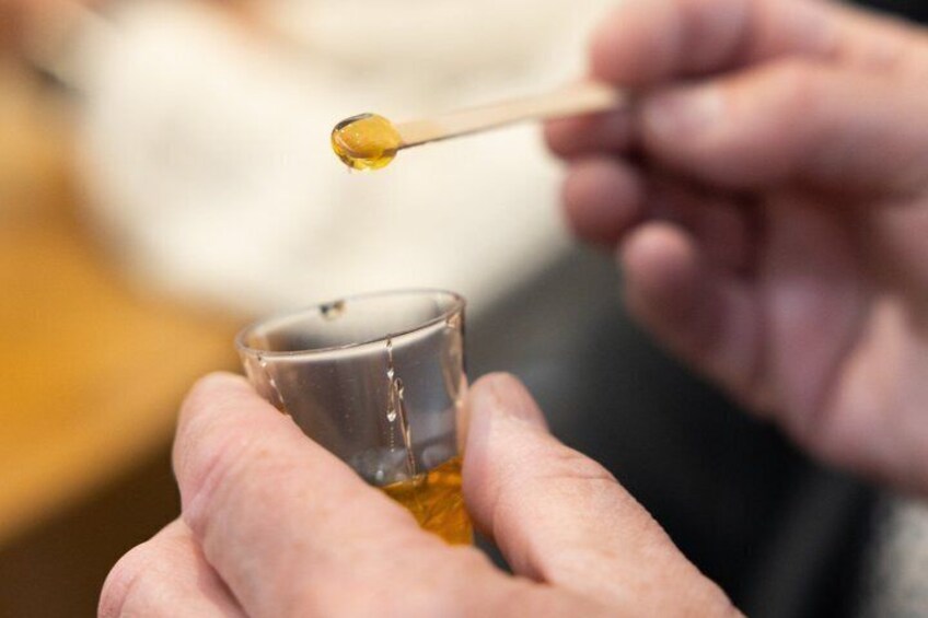 A person holding a small glass and a dropper, dispensing a yellow liquid into the glass. 5