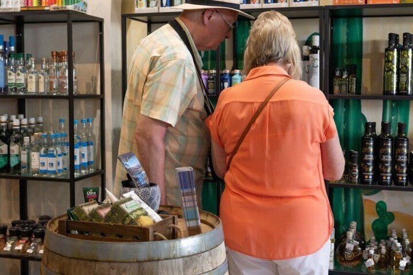 A person in a plaid shirt and a woman in an orange shirt at a bar with shelves of bottles and a barrel. 3