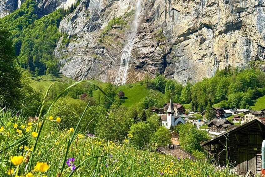 A village with a church, a waterfall, and lush greenery. 5