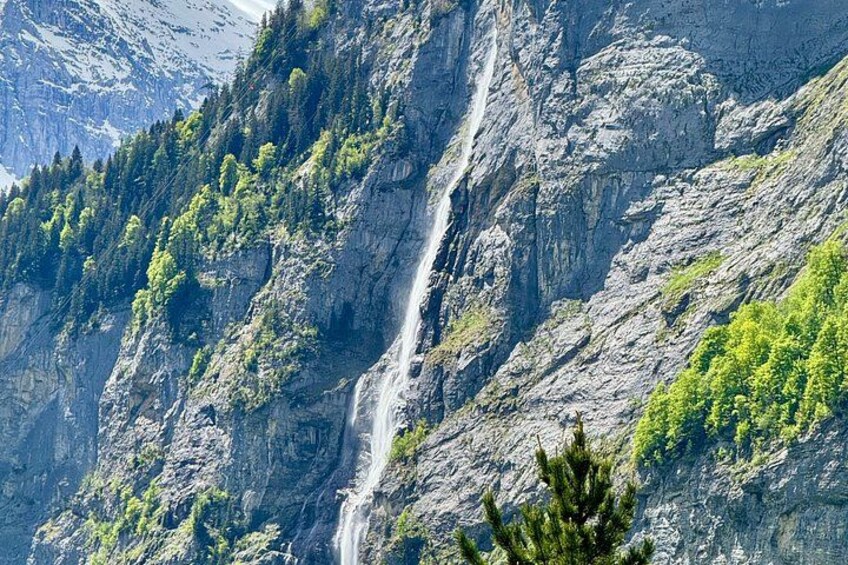 A waterfall cascading down a rocky mountain slope with dense green vegetation. 4