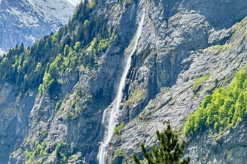 A waterfall cascading down a rocky mountain slope with dense green vegetation. 5