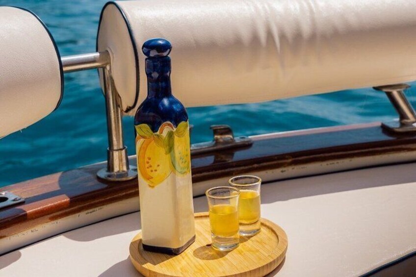A bottle of lemon-flavored liquor and two shot glasses on a wooden tray. 1