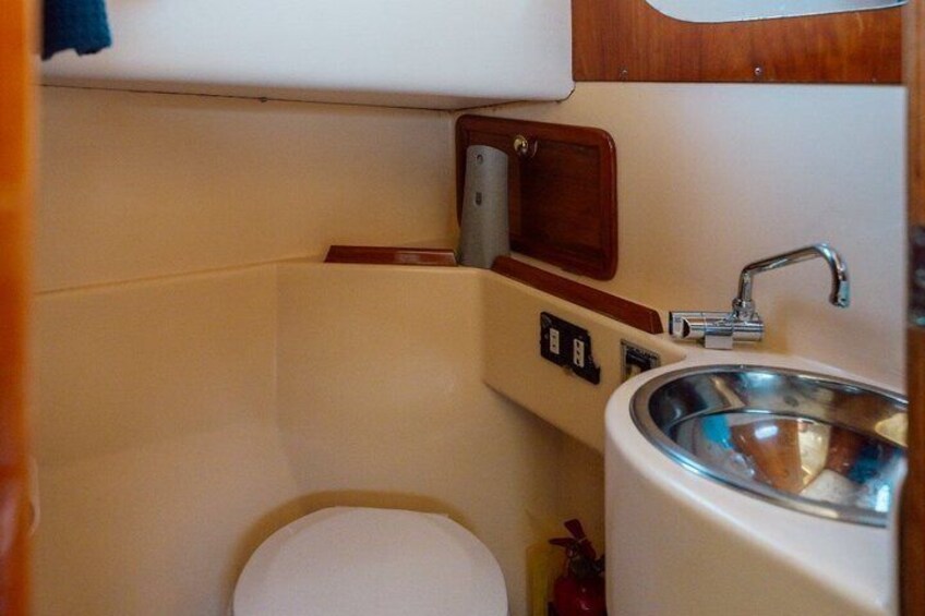 A compact bathroom with a toilet, a sink, and a small cabinet. 5
