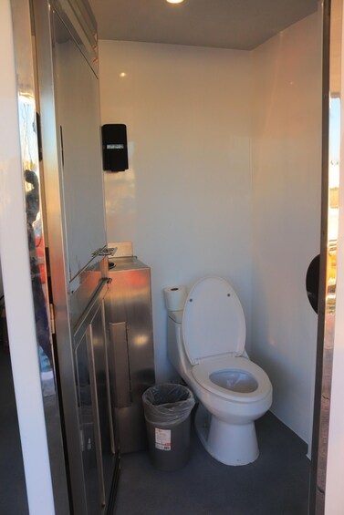A compact bathroom with a white toilet, a trash bin, and a stainless steel sink. 3