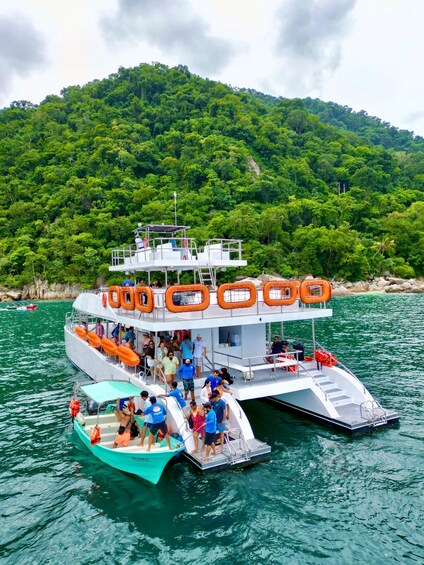 A boat with passengers on a calm sea, surrounded by lush green hills. 1