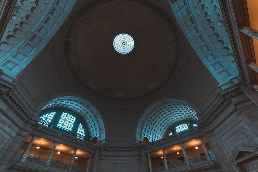 A grand interior with a large circular skylight and arched windows. 5